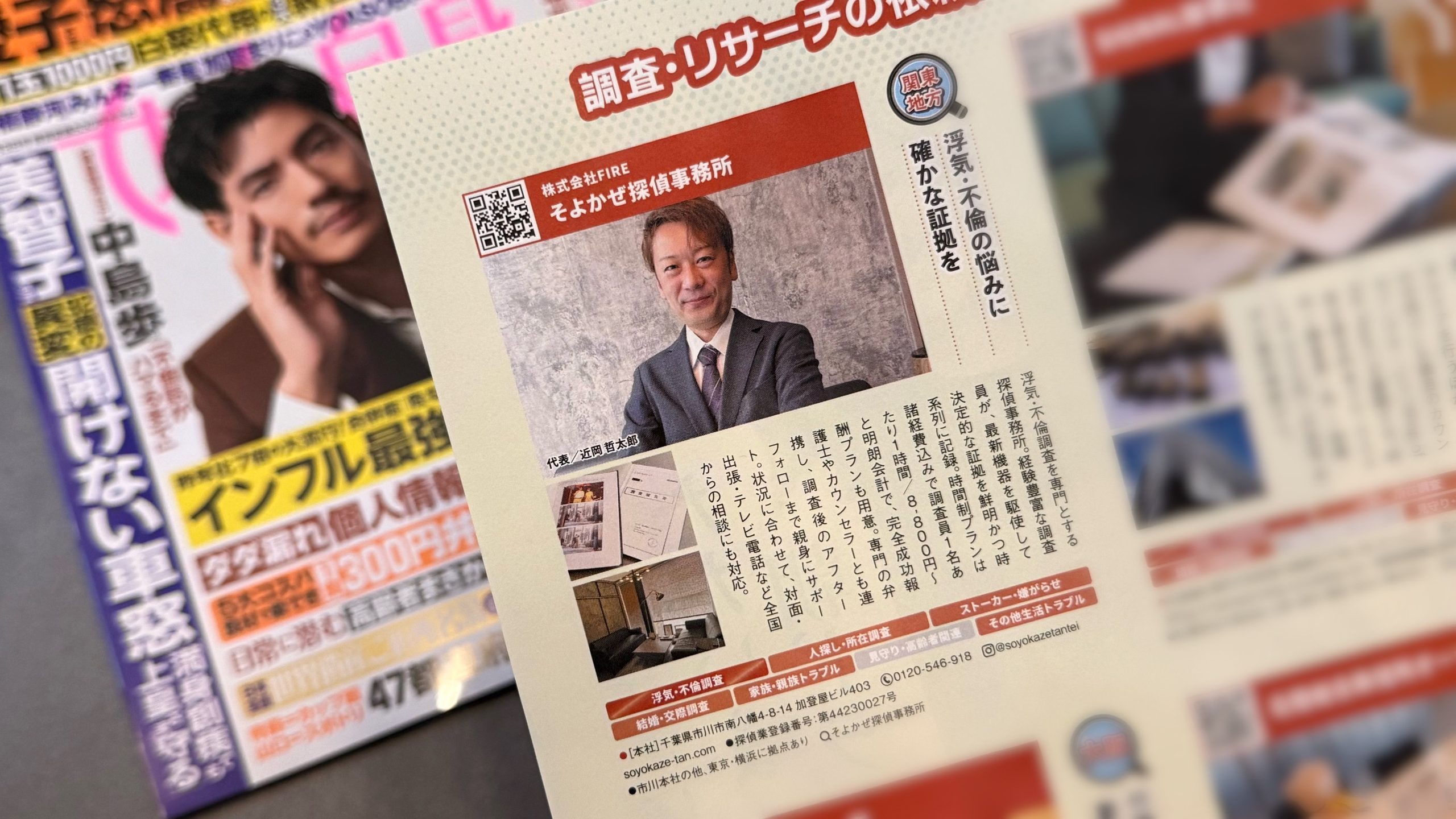 Japanese newspaper page featuring a smiling man in a suit portrait next to a QR code and bold red headline text.